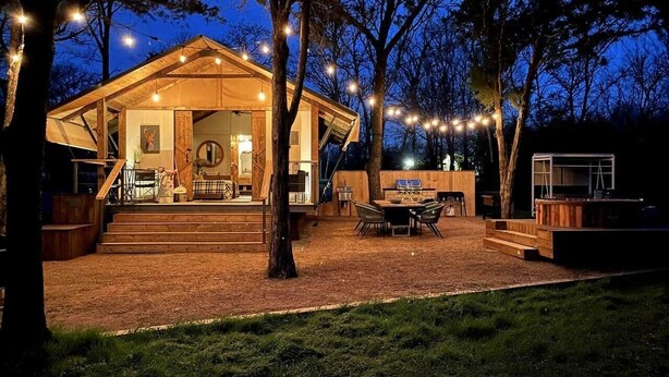 Una baita di legno con un portico coperto, posti a sedere all'aperto e un'area barbecue.