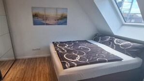 Ein Schlafzimmer mit einem Bett, einem Oberlicht, einem Wandbild und Holzboden.