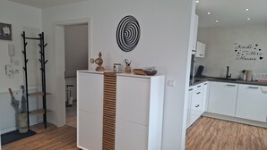 Eine moderne Küche mit weißen Schränken, einer Holzvertäfelung und einem dekorativen Wandbild.