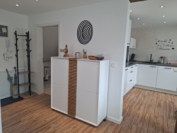 A modern kitchen with white cabinets, a wooden accent panel, and a decorative wall art piece.