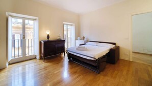 Un dormitorio con cama, cómoda, mesita de noche, lámpara y vistas al exterior.