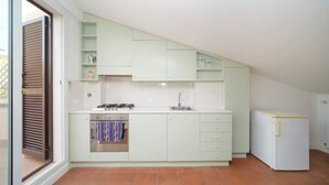 Una cocina con estufa a gas, horno, pileta y refrigerador.