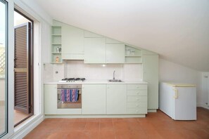 A kitchen with a gas stove, oven, sink, and a refrigerator.