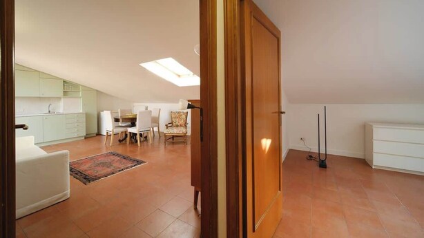 Amplia sala de estar con una mesa de comedor, sillas, un sofá y una cocina al fondo.