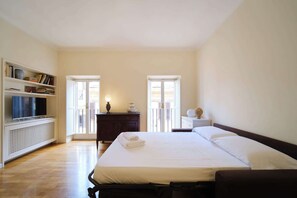Une chambre à coucher avec un lit, une télévision, une commode et une bibliothèque.