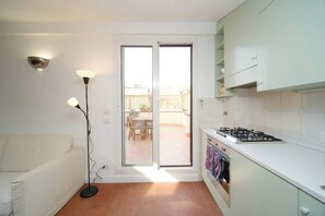 A compact kitchen with a gas stove, white cabinets, and a sliding glass door leading to an outdoor patio.