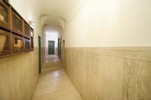 A narrow hallway with a wooden cabinet on the left and a green door at the end.