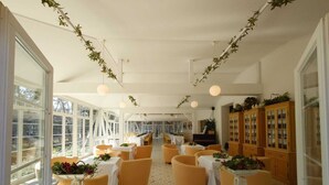 A spacious dining area with high ceilings, large windows, and a tiled floor.