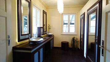 A long, narrow hallway with a dark wooden floor, a large mirror on the left, and a light fixture on the ceiling.