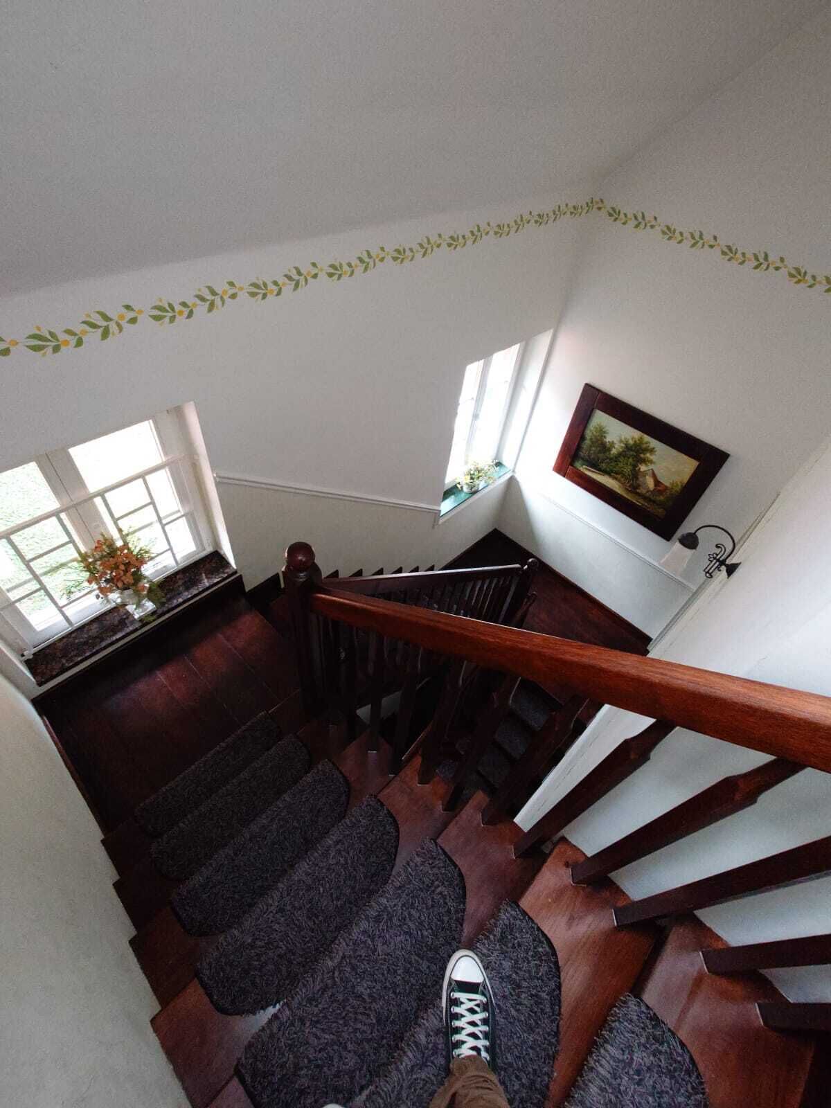 Uma escadaria com degraus de madeira e corrimão, que dá acesso a um andar superior.