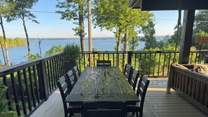 Een houten terras met een tafel en stoelen, uitkijkend op een meer.