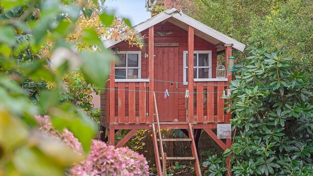 A wooden cabin with a ladder, surrounded by lush greenery. - Apartment 'Anker' with Shared Terrace and Wi-Fi (Cuxhaven)
