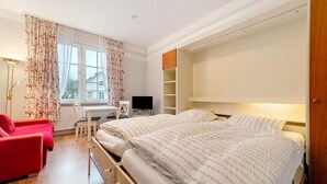A bedroom with a bed, a desk, a chair, and a red sofa. - Apartment 'Anker' with Shared Terrace and Wi-Fi (Cuxhaven)