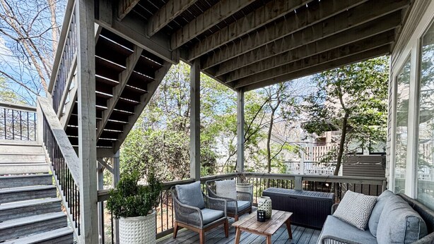 Una terraza techada al aire libre con escaleras, mobiliario de mimbre y una planta en maceta.