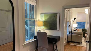 Una habitación con escritorio, silla y un ventanal grande.