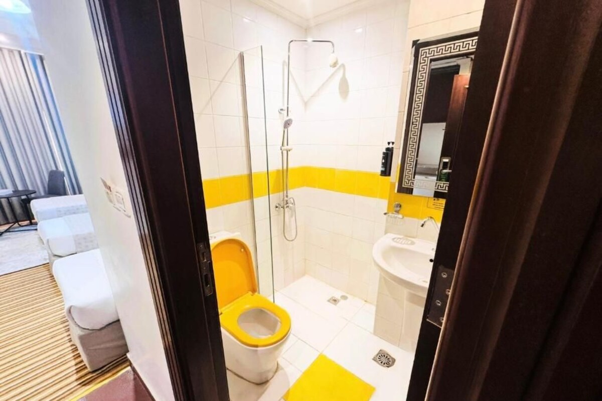 Een badkamer met douche, toilet en wastafel.