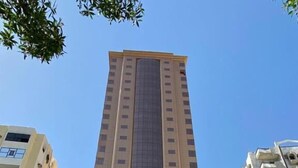 Een hoog, modern gebouw met een centrale glazen gevel en meerdere balkons.