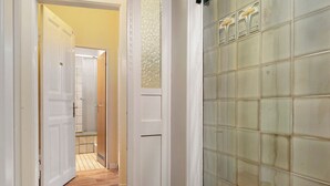 Un corridoio con pavimento in legno, porte bianche e una parete piastrellata con motivo decorativo.