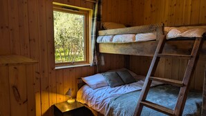 Ein Schlafraum mit Etagenbetten, einem Fenster, einem Nachttisch mit Lampe und einer Leiter.