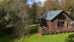 Eine Holzhütte mit einer Terrasse, umgeben von Bäumen.