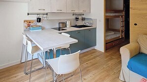 A compact kitchen with a dining area, a bunk bed, and a small seating area. - Cosy apartment near Linga slopes with ski locker and parking (Châtel)