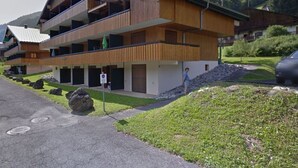 A modern multi-story building with wooden paneling and balconies, set in a mountainous area with a clear sky. - Cosy apartment near Linga slopes with ski locker and parking (Châtel)