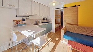 A compact kitchen with a dining area, a bunk bed, and a sofa. - Cosy apartment near Linga slopes with ski locker and parking (Châtel)