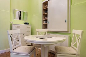 Une pièce comprenant une table ronde, deux chaises, un meuble avec des étagères et un miroir accroché au mur.