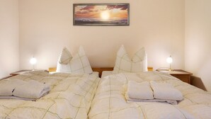 A double bed with a view of the sunset, two bedside tables with lamps, and a painting on the wall.