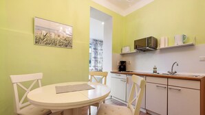 A small kitchen with a dining table and chairs, a microwave, and a coffee maker.