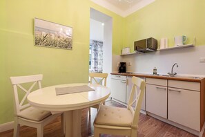 Una pequeña cocina con una mesa y sillas, microondas y cafetera.