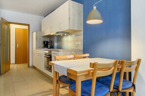 Una cocina compacta con armarios de madera, una mesa de comedor con sillas y una lámpara colgante.