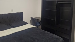 A bedroom with a bed, a desk, and a wardrobe. - Cozy place in Perdeira (Belém)