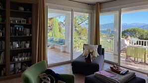 A room with a large sliding glass door leading to a balcony, a sofa, a chair, and a bookshelf. - Villa VISTA - 4 bedrooms, swimming pool, sea view (PORTICCIO)