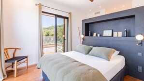 Ein Schlafzimmer mit Bett, Sessel, Deckenventilator und Blick durch eine Glastür.