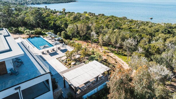 Eine moderne Villa mit Swimmingpool, Sitzgelegenheiten im Freien und Meerblick.
