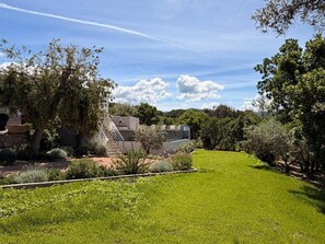 Un jardín bien cuidado con una estructura de piedra, césped y árboles.