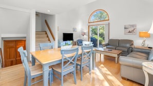 A spacious living area with a dining table, chairs, a sofa, and a television.