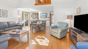 A spacious living area with a sofa, armchair, coffee table, and TV stand.