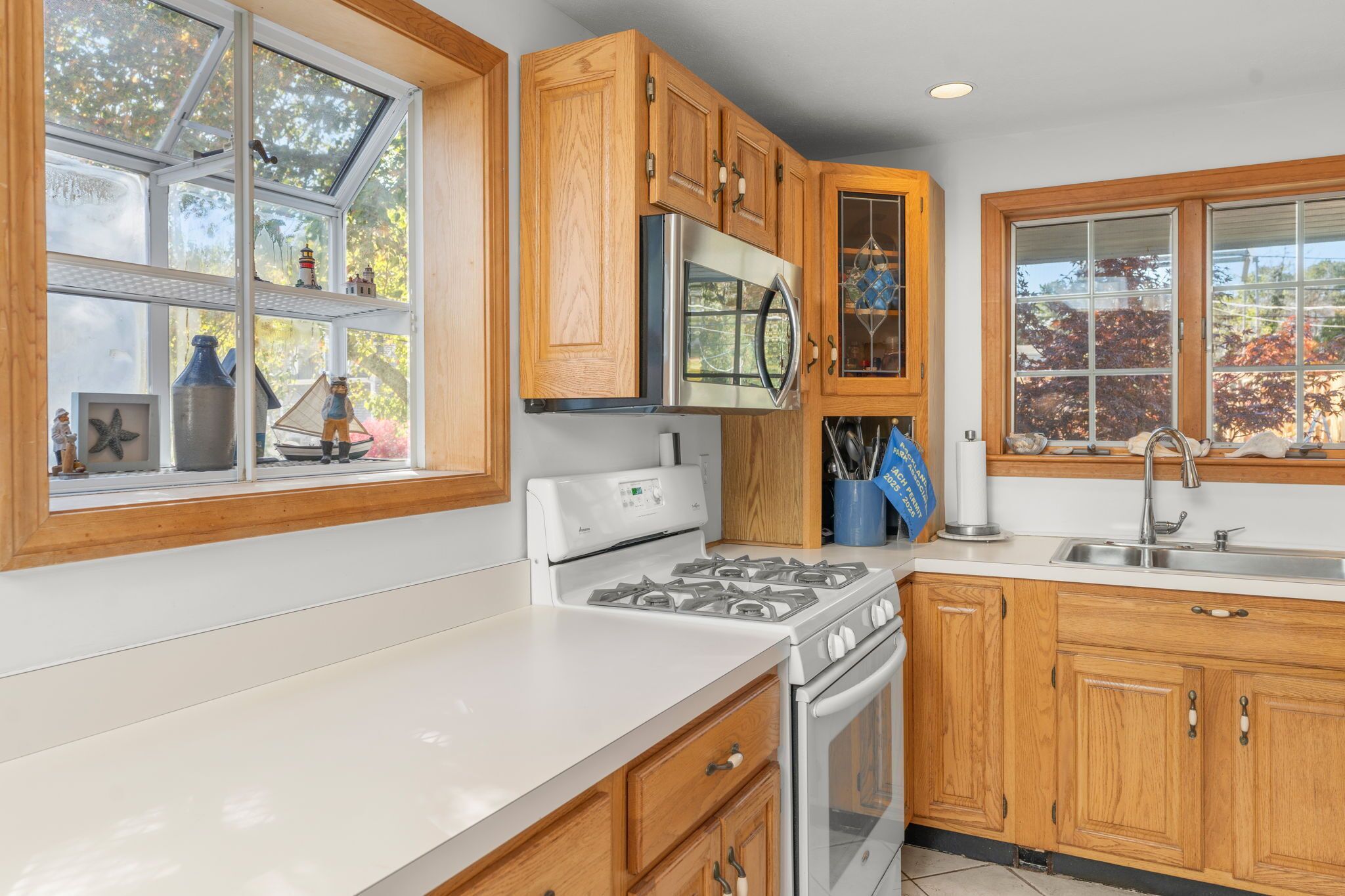 A kitchen with wooden cabinets, a stainless steel microwave, a gas stove, and a sink.