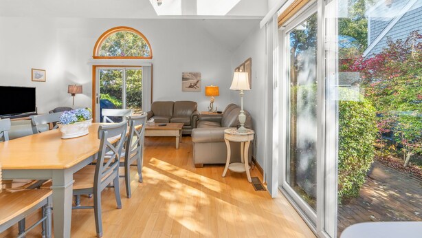 A spacious living area with a dining table, sofas, and a TV.