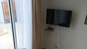 Un saló modern amb dues butaques grises, una taula petita blanca i un televisor de pantalla plana muntat a la pared.