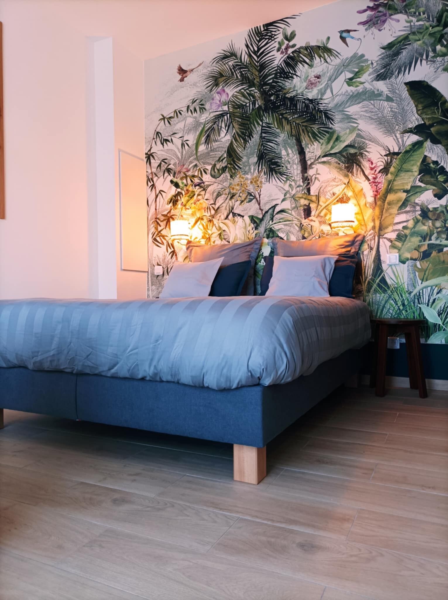 Un dormitorio con una cama, una mesita de noche y un mural en la pared.