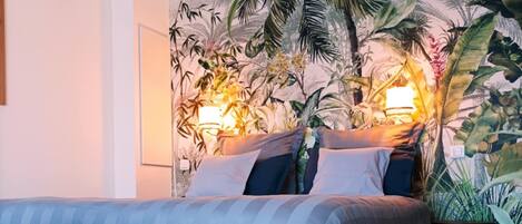 Un dormitorio con una cama, una mesita de noche y un mural en la pared.