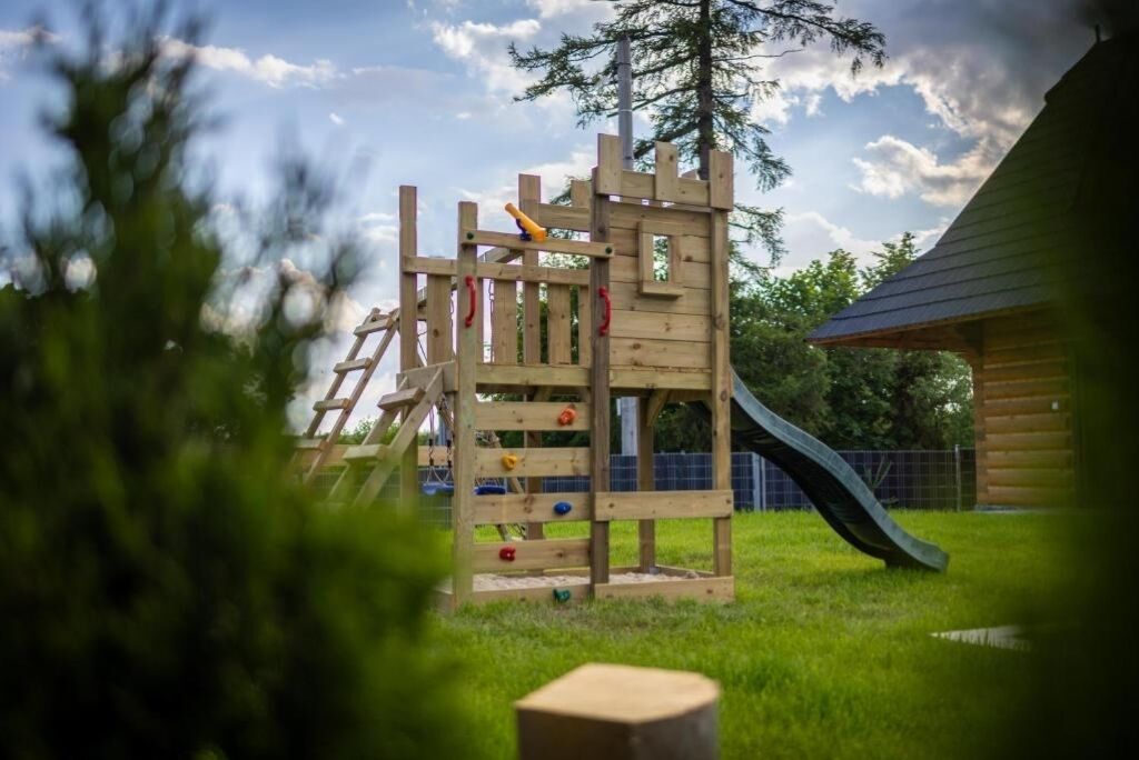 Une structure de jeu en bois comprenant un toboggan, un mur d’escalade et une échelle.