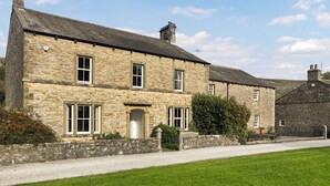 A stone building with a traditional design, featuring multiple windows and a gravel driveway.