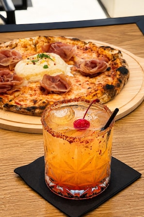 Eine Pizza mit Schinken und einer cremigen Soße auf einem Holzbrett.