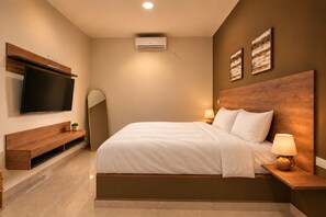 Un dormitorio moderno con una cama grande, lámparas de noche, un televisor de pantalla plana y un aire acondicionado instalado en la pared.