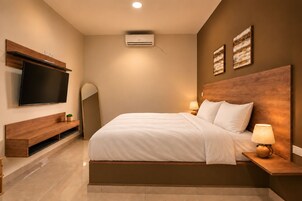 Quarto moderno com cama grande, luminárias de cabeceira, televisão de tela plana e ar condicionado de parede.