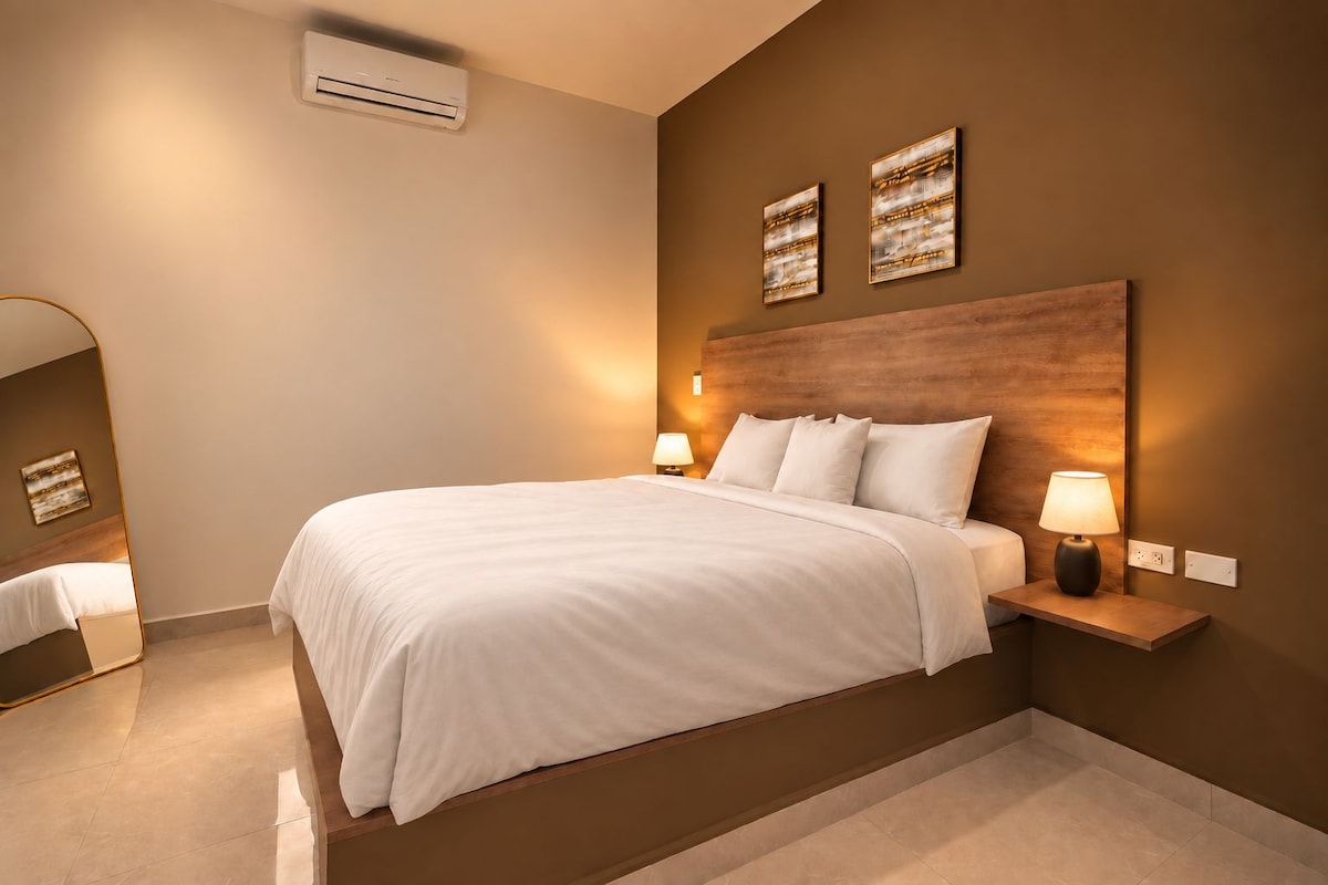 A modern hotel room with a large bed, bedside tables with lamps, and artwork on the walls.